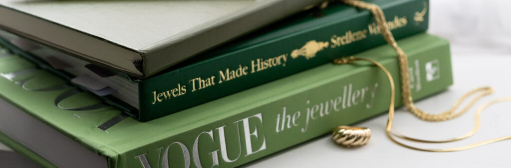 A stack of jewellery books with gold jewellery draped on top